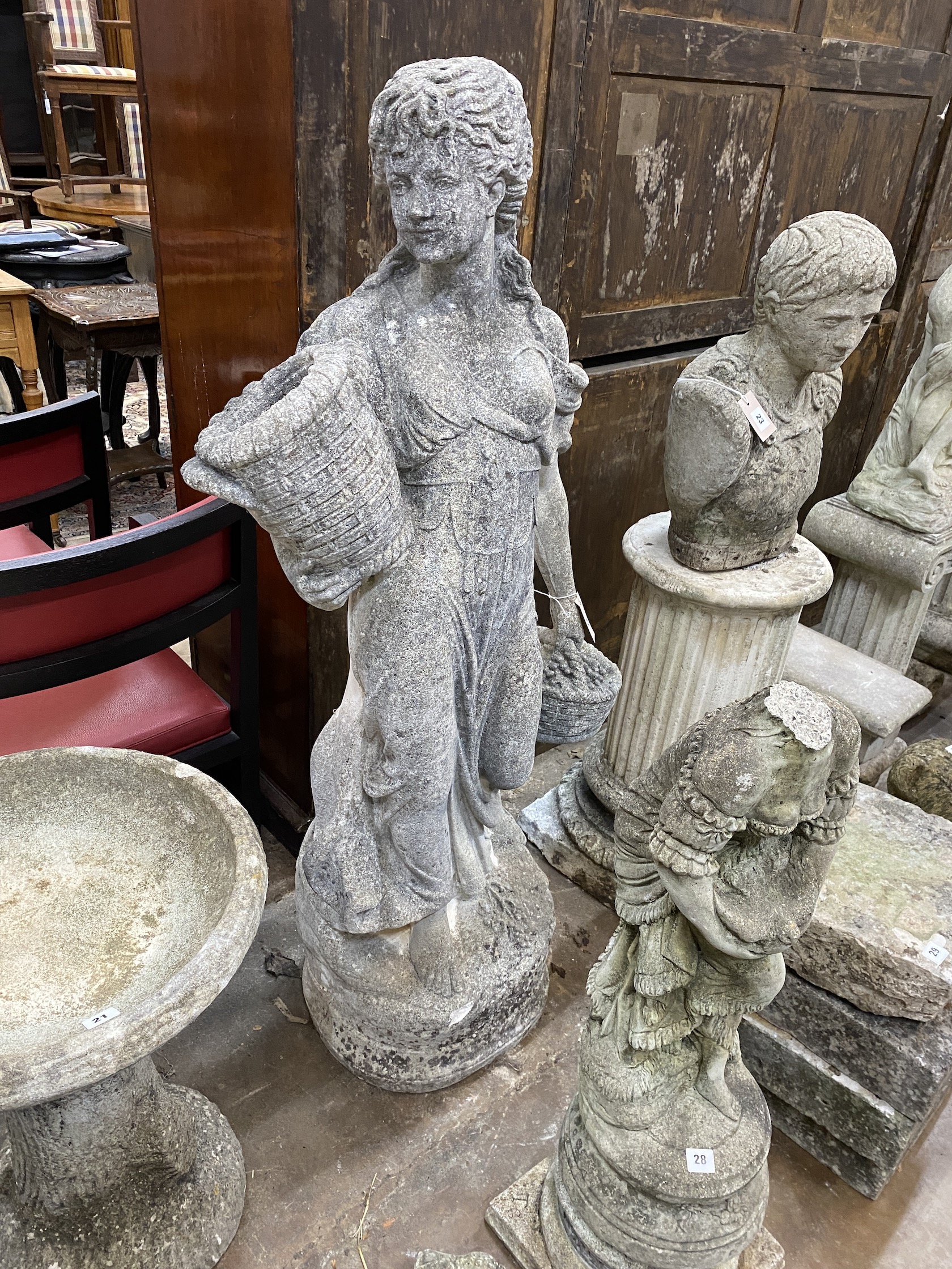 A reconstituted stone garden statue of a lady carrying fruit baskets, height 140cm